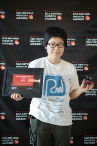 Self-Driving Industry Awards 2026 の会場で、受賞証と RumiCar を手にする RumiCar のメンバー
